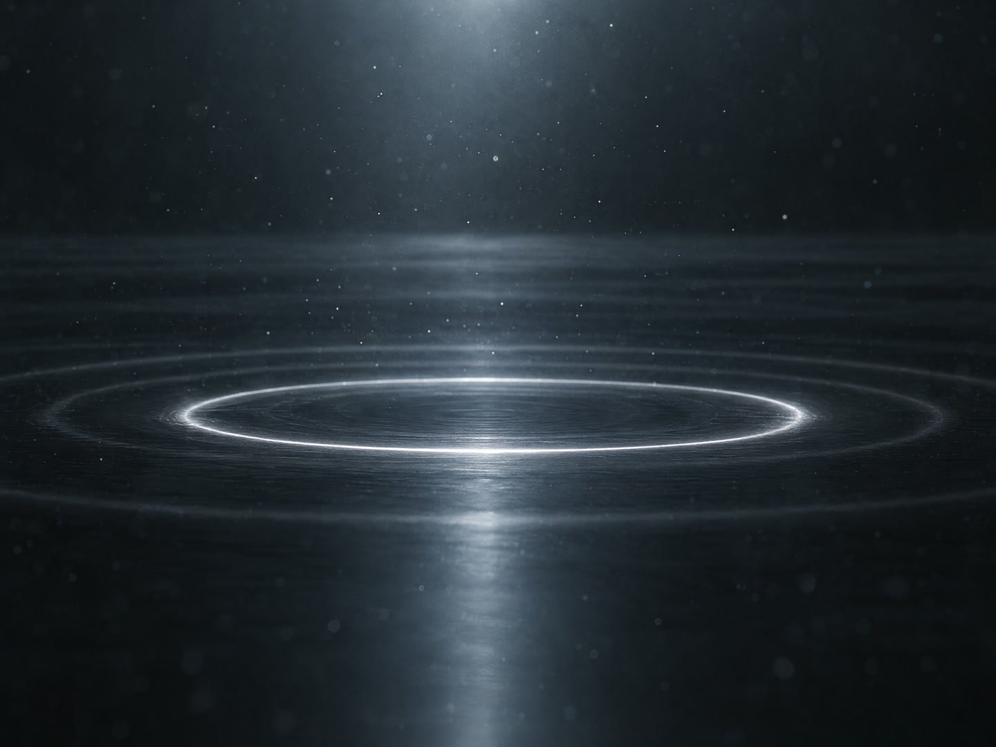 A ring of silver light spreading across a dark surface